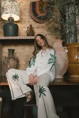 Pantalón de lino color crudo con corte amplio y estampado de palmeras en la parte inferior de las piernas.