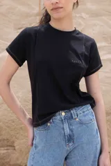 Remera negra de algodón con cuello redondo y mangas cortas. Presenta costuras verticales a los costados y logo bordado en el pecho.