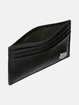 Tarjetero de piel negro, diseño compacto con múltiples ranuras para tarjetas y placa metálica circular con el monograma de Calvin Klein en la parte frontal.