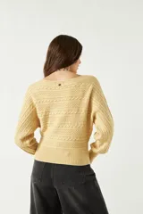 Sweater color amarillo claro, tejido en punto trenzado con cuello redondo y mangas largas abullonadas.