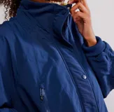 Chaqueta tipo bomber azul marino, con cuello alto y forro interior de piel sintética color verde lima. Presenta cierre frontal con broches y cremallera, y puños y cintura elásticos.