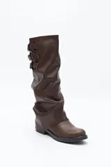 Bota de caña alta confeccionada en poliuretano con diseño de efecto fruncido y puntera redondeada. Presenta tres hebillas metálicas decorativas en el lateral superior de la caña y taco bajo.