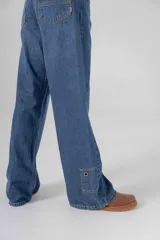 Pantalón de jean azul, corte recto y extra largo, con aplique de denim y ojalillo en una pierna.