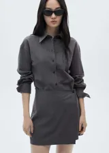 Minivestido gris con estampado de raya diplomática, diseño cruzado con cierre de botones en la parte delantera, manga larga con puños abotonados, cuello camisero y diseño entallado.