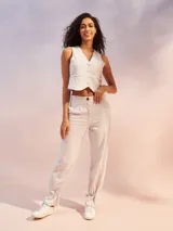 Pantalón de vestir color beige claro, de corte holgado con pinzas frontales y talle alto. El bajo del pantalón se ajusta con un lazo.