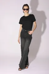 Pantalón de jean gris oscuro de corte acampanado, con tachas metálicas plateadas en los laterales.