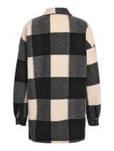 Sobrecamisa larga con estampado a cuadros grandes en tonos blanco, gris y negro. Tiene cuello camisero, cierre con botones a presión, dos bolsillos de parche en el pecho y corte recto.