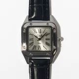 Reloj de pulsera con caja cuadrada plateada y correa de cuero negra con textura.