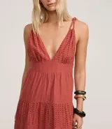 Vestido midi de corte evasé confeccionado en tejido laise de algodón. Presenta escote en V con busto fruncido, breteles finos torcidos con nudos y falda con recortes fruncidos y bordados calados.