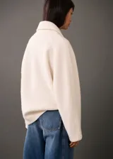 Chaqueta marrón de tejido mezcla de lana con forro interior, cuello camisero, cierre delantero con cremallera, dos bolsillos laterales y diseño oversize.