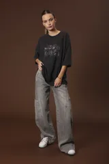 Remera negra de corte oversize con estampado abstracto en tonos rojos, grises y blancos.