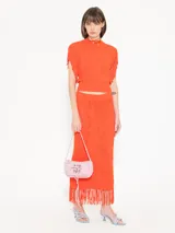 Pollera larga tejida color naranja, de corte ajustado y calados.