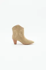 Bota corta de cuero gamuzado color beige, estilo texana, con taco medio de 6 cm y diseño de mariposa en los laterales.