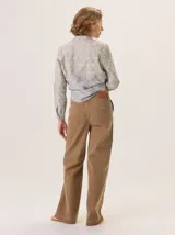 Pantalón de jean color marrón claro, tiro medio/alto, con pierna recta y holgada. Presenta costuras a contratono y cierre frontal con botón.