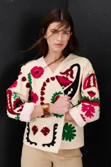 Chaqueta color crudo con bordados florales en tonos rojo, verde y negro.