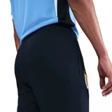 Pantalón de entrenamiento Nike para hombre de la selección uruguaya, color azul marino, con puños ajustados en los tobillos y cordón en la cintura. Presenta el escudo de la AUF con cuatro estrellas bordado en la pierna izquierda y el logo de Nike en blanco en la pierna derecha.