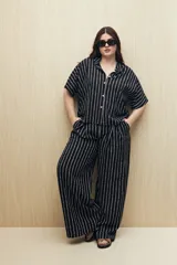 Pantalón ancho de viscosa con estampado a rayas verticales blancas sobre fondo negro, cintura elastizada y caída fluida.