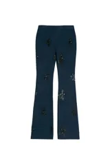 Pantalón de jean azul oscuro, corte flare, tiro medio y apliques de lentejuelas negras formando motivos florales.