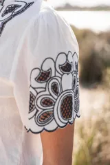 Blusa blanca de algodón con bordados florales en azul marino en el frente y las mangas.