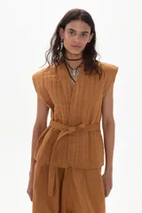 Chaleco color caramelo de lino acolchado con cuello en V, sin mangas y con lazo para atar en la cintura.