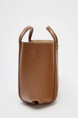 Bolso mini city color marrón con asa de mano y asa bandolera extraíble. Detalle de pespuntes en contraste y bolsa interior extraíble con cierre mediante cremallera.
