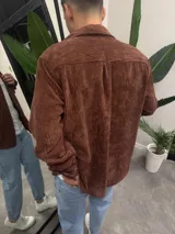 Sobrecamisa marrón de pana con cuello clásico, cierre abotonado y bolsillo de parche en el pecho.