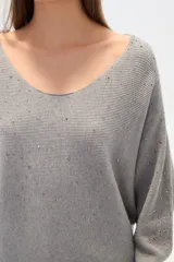 Sweater negro de tejido acanalado, corte holgado tipo murciélago con mangas largas ajustadas en puños. Escote bote adornado con apliques de pedrería plateada que se extienden por los hombros y mangas.