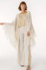 Ruana de punto color beige con cuello alto y flecos.