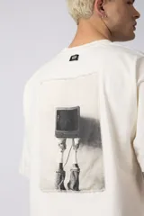 Remera color crema de corte oversize con la inscripción '90's' bordada en el frente y parche con imagen en la espalda.