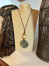 Collar con cordón marrón, cuentas de madera y dije circular con estampado de leopardo.