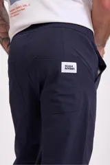Pantalón de vestir azul marino, de corte recto, con bolsillos laterales y traseros. Se ajusta a la cintura con cinturón de cuero marrón.