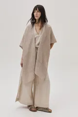 Ruana beige de tejido de punto acanalado con mangas cortas.