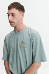 Remera de manga corta color verde con estampado de flores y texto en la espalda.