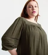 Blusa verde militar de viscosa con escote cuadrado y mangas 3/4 abullonadas con elástico en los puños. Presenta inserciones en el escote y en las mangas.