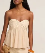 Blusa color beige sin breteles, confeccionada en viscolino con 15% de lino, con escote corazón, fruncidos y lastex en la espalda. La prenda tiene cuerditas aplicadas en el busto.