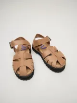 Sandalias romanas de cuero color tostado, con suela de goma y hebilla metálica lateral.