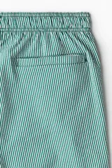 Short de baño de sirsaca a rayas verticales verdes y blancas, con aberturas laterales cortas, elástico y cordón ajustable en la cintura, bolsillos laterales, bolsillo trasero con cierre autoadherente y suspensor interior de malla.