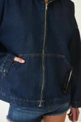 Campera estilo bomber de jean con canesú en la espalda, capucha, cierre metálico y dos bolsillos canguro en el frente.