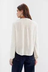 Camisa de calce recto en color crudo, con escote en V y pechera bordada en hilo con aplicaciones de espejos.