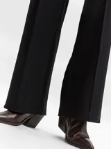 Pantalón de vestir negro con pinzas frontales, corte ajustado y pierna ancha.