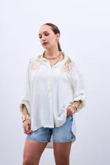 Camisa color crudo con bordado de lentejuelas doradas en el frente, de corte holgado y mangas largas con lazo en los puños.