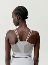 Top deportivo color gris con textura acanalada, tirantes finos y logo en el frente.