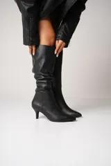 Botas de cuero negro con caña alta arrugada, taco kitten heel y cierre lateral.