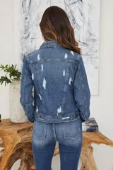 Chaqueta de jean azul con botones, cuello clásico, bolsillos delanteros y diseño con roturas.