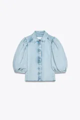 Blusa de denim celeste con cuello solapa y mangas abullonadas por debajo del codo. Cierre frontal con botones.
