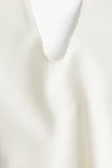 Top blanco con escote halter en V y corte acampanado.