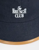 Piluso de denim azul con borde marrón y bordado frontal con la frase "The Brunch Club".
