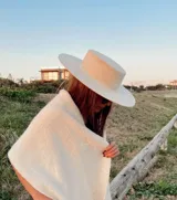 Sombrero de ala ancha color crudo, con copa cilíndrica alta y ala recta de 10 cm.