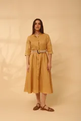 Vestido midi color mostaza, estilo camisero, con cuello mao, mangas 3/4 y cinturón trenzado.
