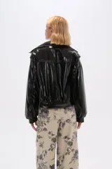 Chaqueta de eco-cuero color bordó, holgada, con cierre frontal, cuello tipo camisa y bolsillos laterales.